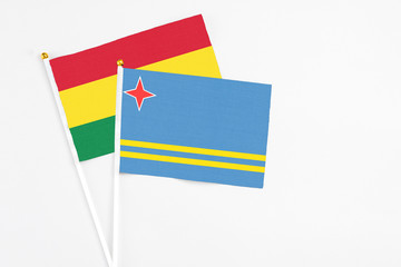 Aruba and Bolivia stick flags on white background. High quality fabric, miniature national flag. Peaceful global concept.White floor for copy space.