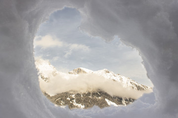 Window of snow bunker, igloo with winter mountain peaks view