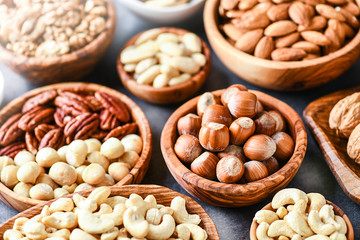 A variety of nuts in wooden bowls from top view. Walnuts, cashew, almond, pistachio, pecan, hazelnut, macadamia nut. Healthy super food selection.
