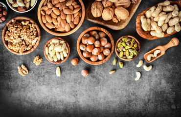 A variety of nuts in wooden bowls from top view. Walnuts, cashew, almond, pistachio, pecan, hazelnut, macadamia and peanut mix selection. Healthy fitness super food banner or panorama.