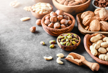 A variety of nuts in wooden bowls from top view. Walnuts, cashew, almond, pistachio, pecan,...