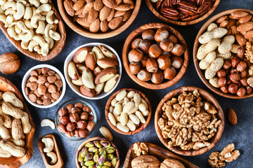 Mixed nuts in wooden bowls on black stone table. Almonds, pistachio, walnuts, cashew, hazelnut. Top view nut photo.