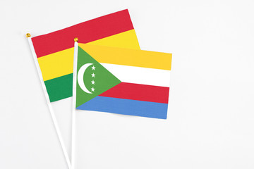 Comoros and Bolivia stick flags on white background. High quality fabric, miniature national flag. Peaceful global concept.White floor for copy space.