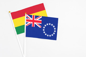 Cook Islands and Bolivia stick flags on white background. High quality fabric, miniature national flag. Peaceful global concept.White floor for copy space.