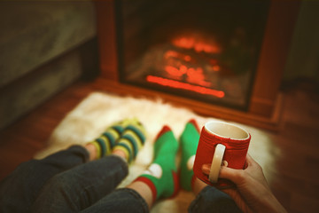 Feet in wool socks near fireplace in winter time