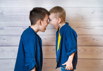 Portrait of two brothers standing head to head and screaming in studio. Boys wearing the same...