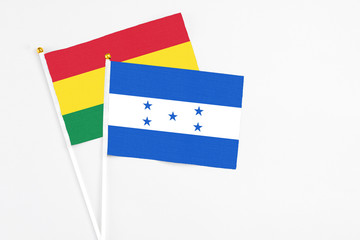 Honduras and Bolivia stick flags on white background. High quality fabric, miniature national flag. Peaceful global concept.White floor for copy space.