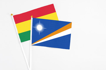 Marshall Islands and Bolivia stick flags on white background. High quality fabric, miniature national flag. Peaceful global concept.White floor for copy space.