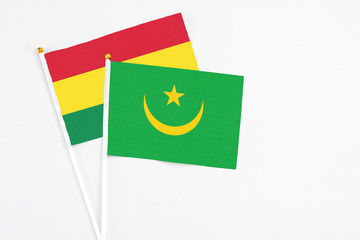 Mauritania and Bolivia stick flags on white background. High quality fabric, miniature national flag. Peaceful global concept.White floor for copy space.