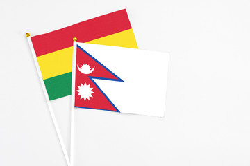 Nepal and Bolivia stick flags on white background. High quality fabric, miniature national flag. Peaceful global concept.White floor for copy space.