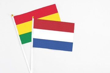 Netherlands and Bolivia stick flags on white background. High quality fabric, miniature national flag. Peaceful global concept.White floor for copy space.