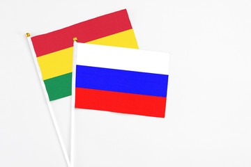 Russia and Bolivia stick flags on white background. High quality fabric, miniature national flag. Peaceful global concept.White floor for copy space.