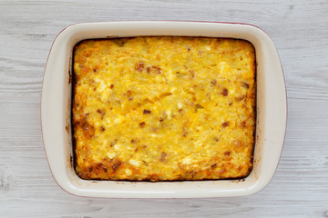Homemade Cheesy Amish Breakfast Casserole on a white wooden surface, top view. Flat lay, overhead, from above. Closeup.