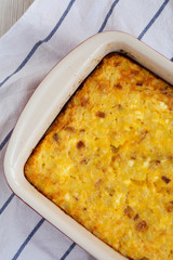 Homemade Cheesy Amish Breakfast Casserole on a white wooden surface, top view. Flat lay, overhead, from above. Closeup.