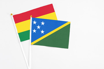 Solomon Islands and Bolivia stick flags on white background. High quality fabric, miniature national flag. Peaceful global concept.White floor for copy space.