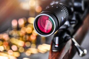 Close up of rifle scope hunting on wooden ammonition background. Hunt sniper gun, optics scopes...