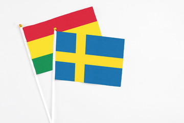 Sweden and Bolivia stick flags on white background. High quality fabric, miniature national flag. Peaceful global concept.White floor for copy space.