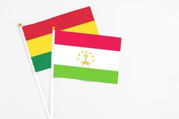 Tajikistan and Bolivia stick flags on white background. High quality fabric, miniature national flag. Peaceful global concept.White floor for copy space.