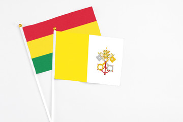 Vatican City and Bolivia stick flags on white background. High quality fabric, miniature national flag. Peaceful global concept.White floor for copy space.