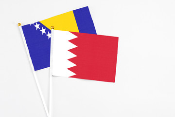 Bahrain and Bosnia Herzegovina stick flags on white background. High quality fabric, miniature national flag. Peaceful global concept.White floor for copy space.