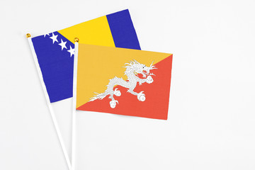 Bhutan and Bosnia Herzegovina stick flags on white background. High quality fabric, miniature national flag. Peaceful global concept.White floor for copy space.