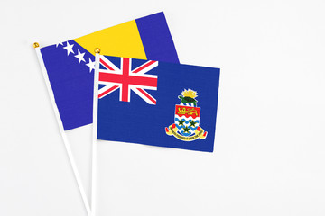 Fototapeta premium Cayman Islands and Bosnia Herzegovina stick flags on white background. High quality fabric, miniature national flag. Peaceful global concept.White floor for copy space.