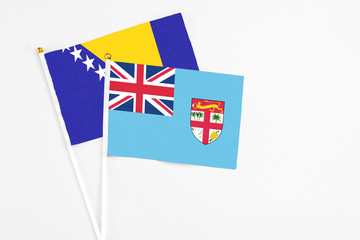 Fiji and Bosnia Herzegovina stick flags on white background. High quality fabric, miniature national flag. Peaceful global concept.White floor for copy space.