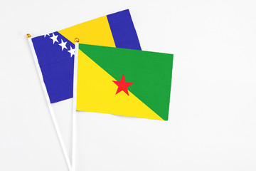 French Guiana and Bosnia Herzegovina stick flags on white background. High quality fabric, miniature national flag. Peaceful global concept.White floor for copy space.