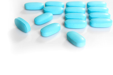Obraz na płótnie Canvas blue pills on white background close-up
