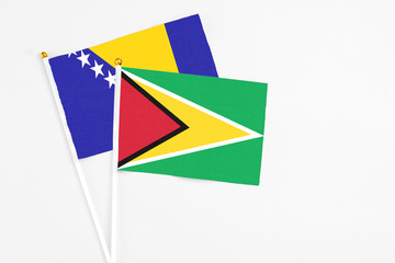 Guyana and Bosnia Herzegovina stick flags on white background. High quality fabric, miniature national flag. Peaceful global concept.White floor for copy space.