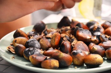 fried chestnuts and peels on a plate. chestnut in the hands. healthy vegetarian food, snacks