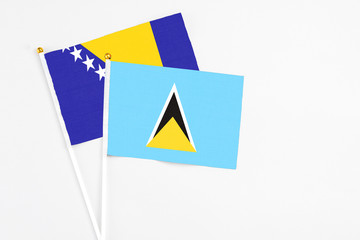 Saint Lucia and Bosnia Herzegovina stick flags on white background. High quality fabric, miniature national flag. Peaceful global concept.White floor for copy space.