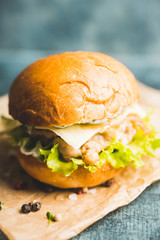 Fresh tasty burgers with roasted turkey cutlet, salad, cheese and different herbs on the rustic background. Selective focus. Shallow depth of field.