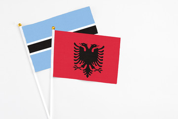 Albania and Botswana stick flags on white background. High quality fabric, miniature national flag. Peaceful global concept.White floor for copy space.