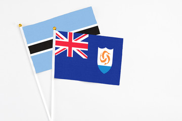 Anguilla and Botswana stick flags on white background. High quality fabric, miniature national flag. Peaceful global concept.White floor for copy space.