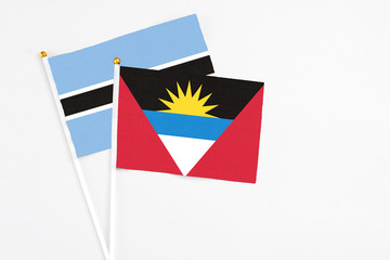 Antigua and Barbuda and Botswana stick flags on white background. High quality fabric, miniature national flag. Peaceful global concept.White floor for copy space.