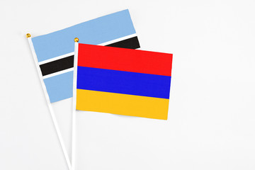 Armenia and Botswana stick flags on white background. High quality fabric, miniature national flag. Peaceful global concept.White floor for copy space.