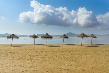 Umbrellas on the beach by the sea. La Manga del Mar Menor. Murcia, Spain