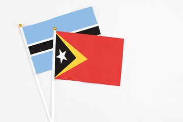 East Timor and Botswana stick flags on white background. High quality fabric, miniature national flag. Peaceful global concept.White floor for copy space.