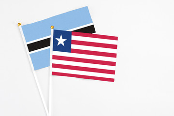 Liberia and Botswana stick flags on white background. High quality fabric, miniature national flag. Peaceful global concept.White floor for copy space.