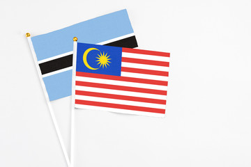 Malaysia and Botswana stick flags on white background. High quality fabric, miniature national flag. Peaceful global concept.White floor for copy space.