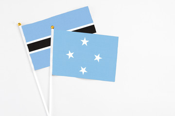 Micronesia and Botswana stick flags on white background. High quality fabric, miniature national flag. Peaceful global concept.White floor for copy space.