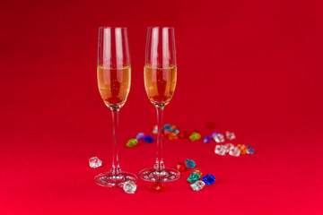 glasses of champagne on red background with sparkling crystal stones on base. New year or romantic celebration. Luxury. Free space