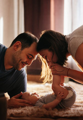 Baby with his parents playing on the bed. Happy family at home. Lifestyle cozy photos. Little boy 4...