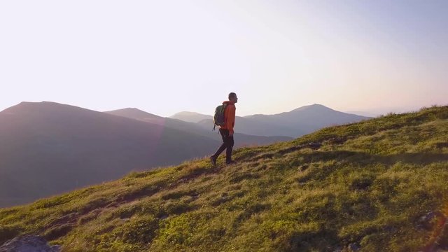 Tourist hiker with a backpack running on mountain path in Carpathian mountains. Man tourist jogging in rocky desert terrain.