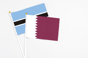 Qatar and Botswana stick flags on white background. High quality fabric, miniature national flag. Peaceful global concept.White floor for copy space.