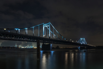 Fototapeta premium Illuminated Historical Iron Bridge across the River Rhine connecting Duisburg and Krefeld Uerdingen At Night