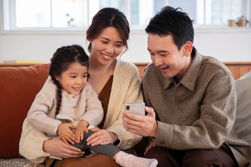 リビングでスマホを見る親子の団欒風景