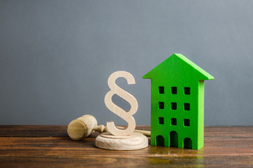Green house and paragraph figurine with a judge gavel. Concept legislation on residential buildings...