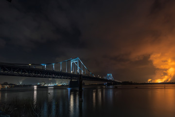 Naklejka premium Illuminated Historical Iron Bridge across the River Rhine connecting Duisburg and Krefeld Uerdingen At Night